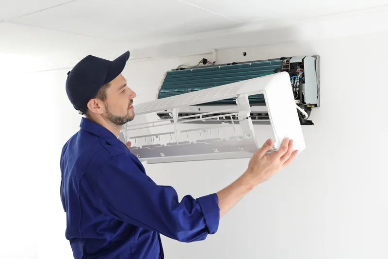 Image illustrates a man from one of the reputed AC companies, is doing maintenance of AC.