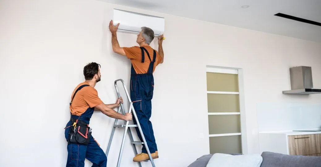 Images shows that a man is in the ladder doing Air conditioning services Petersburg.