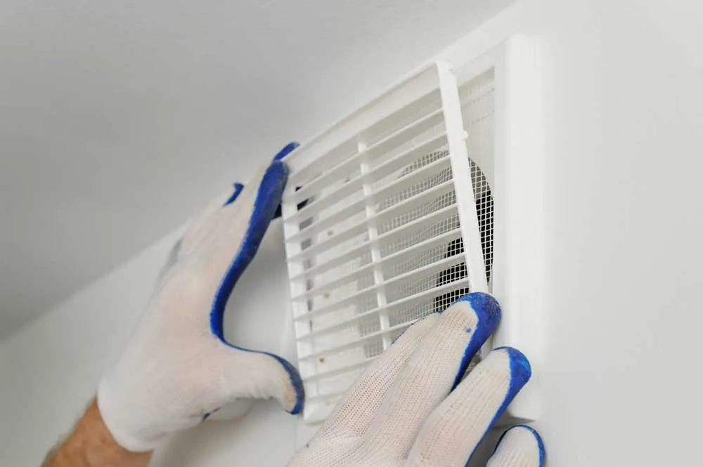 Image shows that a man is repairing the AC wind and providing AC Repair Services.